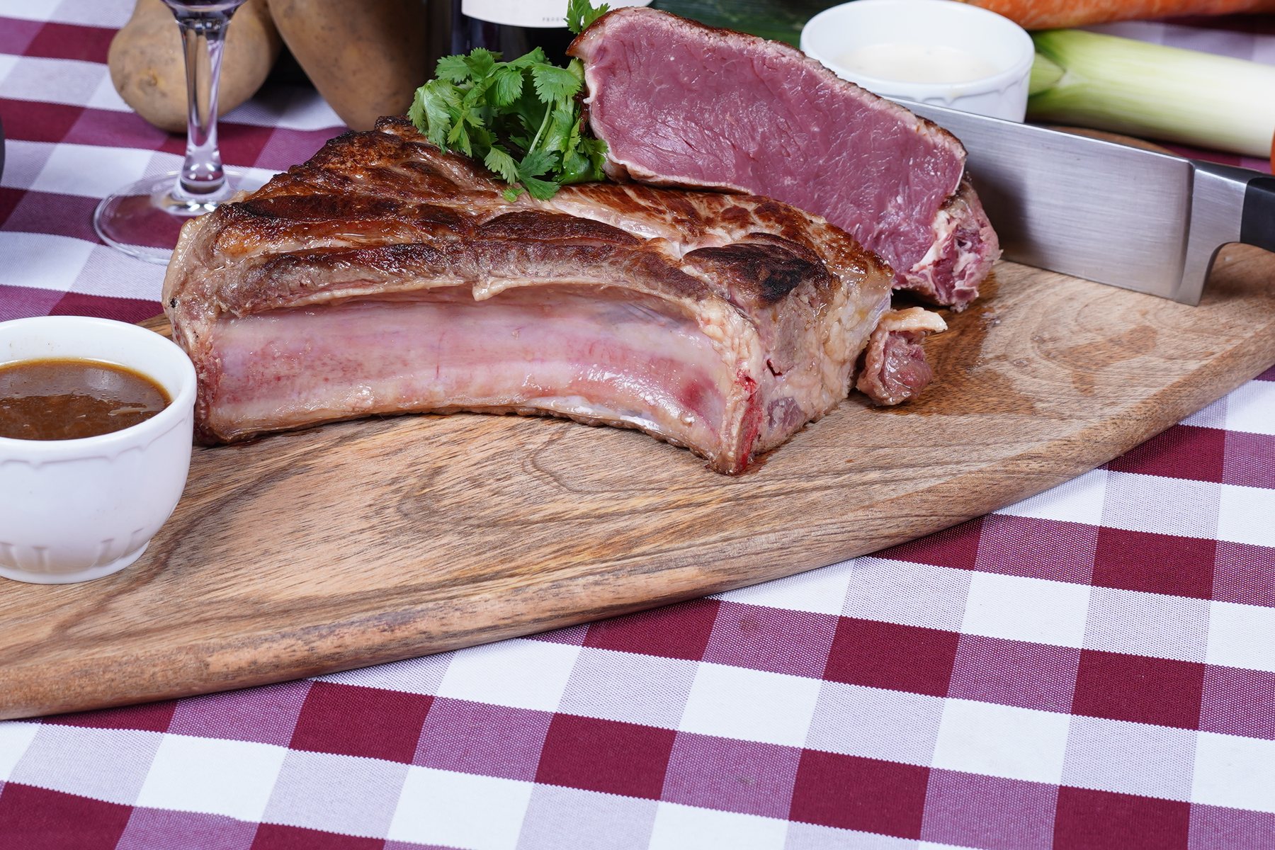 Une côte de bœuf limousine grillée et tranchée sur sa planche, avec une sauce maison et des légumes
