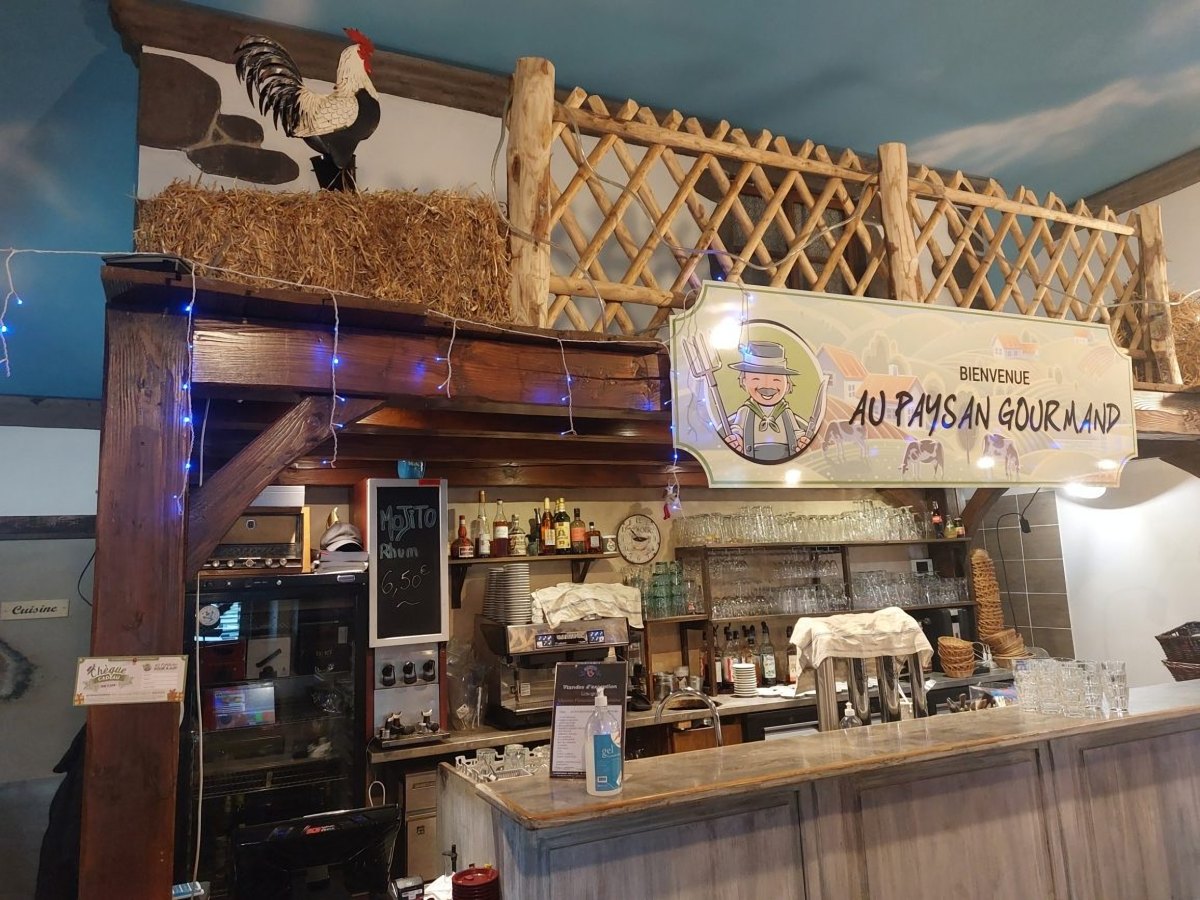 Le bar sous la mezzanine en bois, et l'enseigne « Bienvenue au Paysan Gourmand »